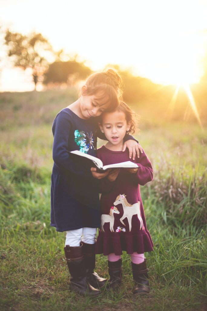 Dwójka dzieci w różnym wieku czyta jedną książkę